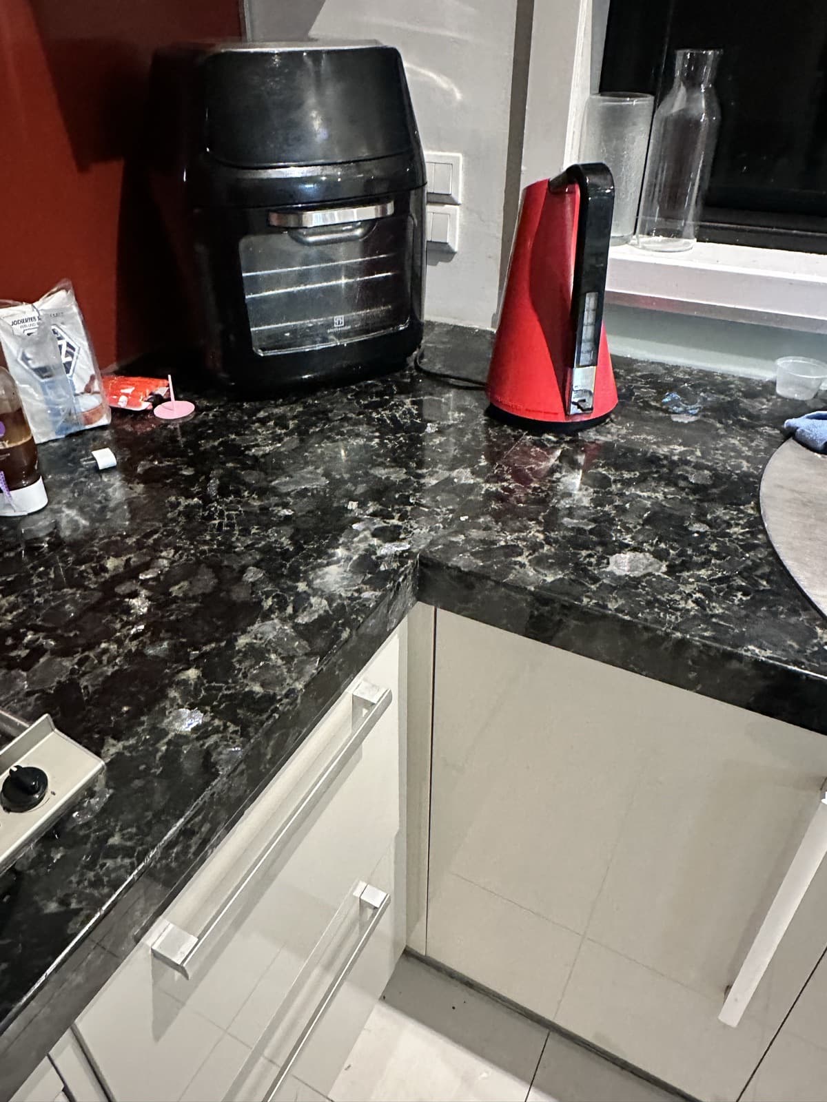 After: the dark stone benchtop with the chip repaired and the surface even again.