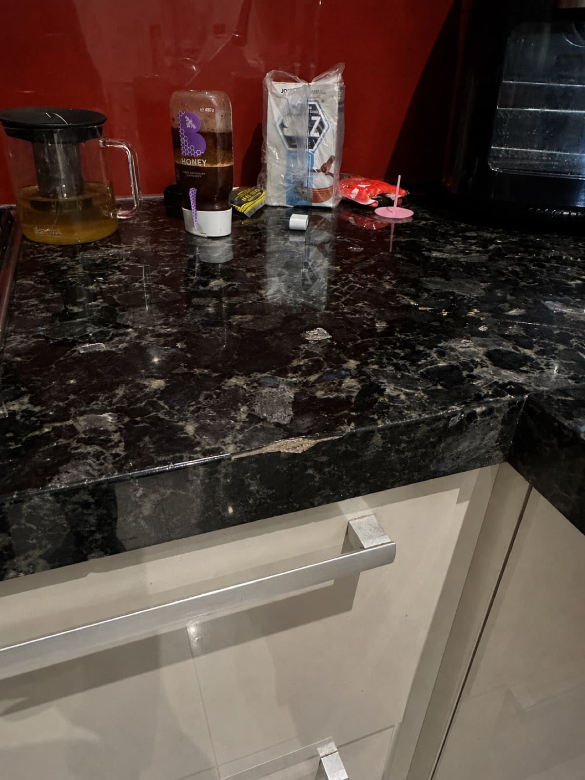 Before: a chip in the surface of a dark stone kitchen benchtop.