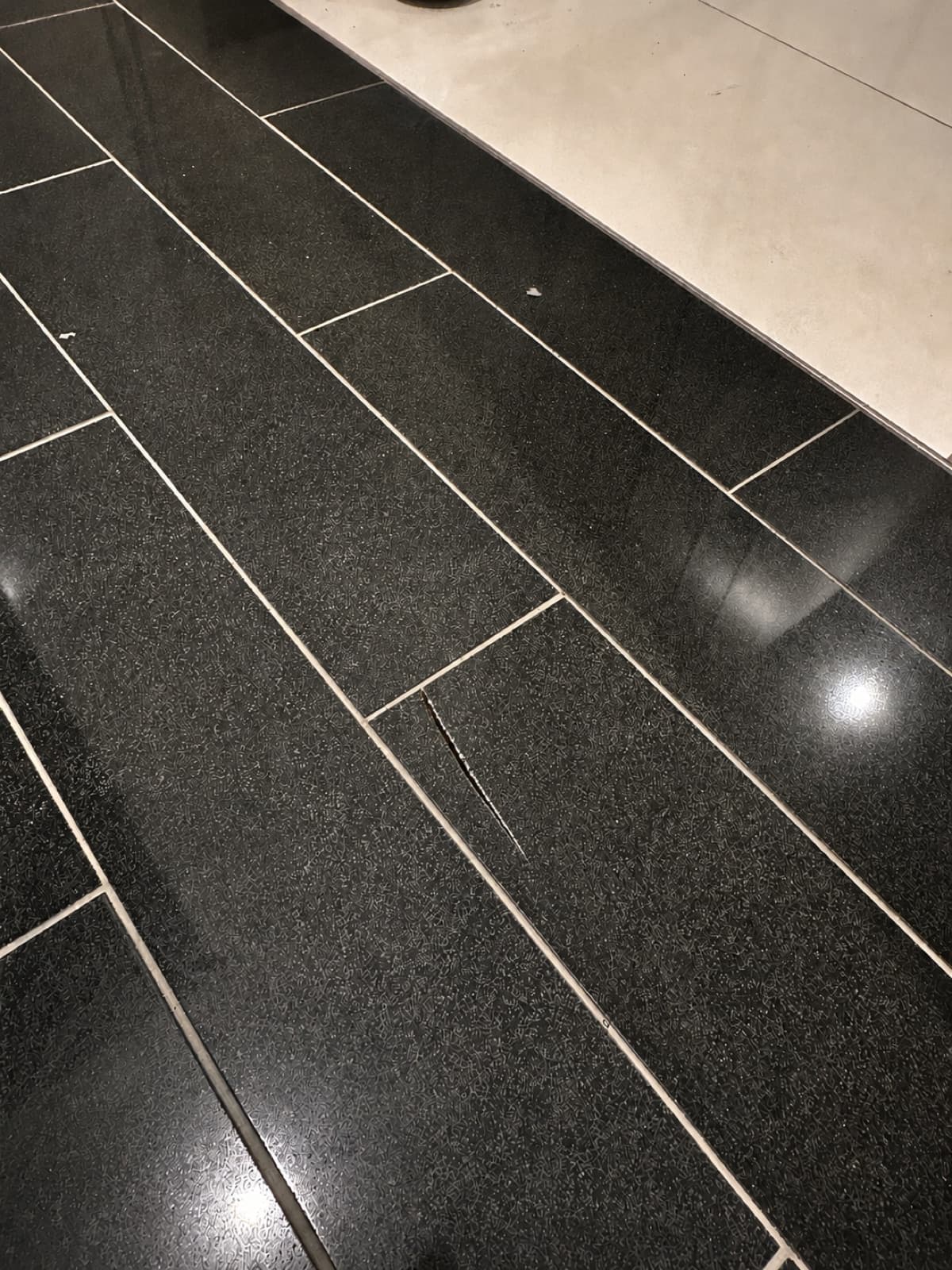 Before: a damaged dark floor tile in a laundry.